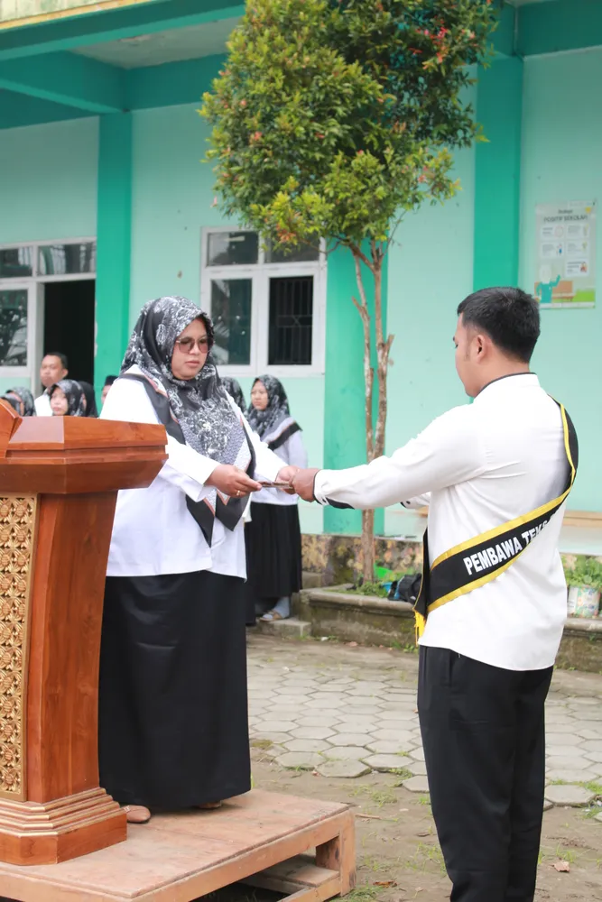 Ajudan menyerahkan teks Pancasila kepada Kepala Sekolah