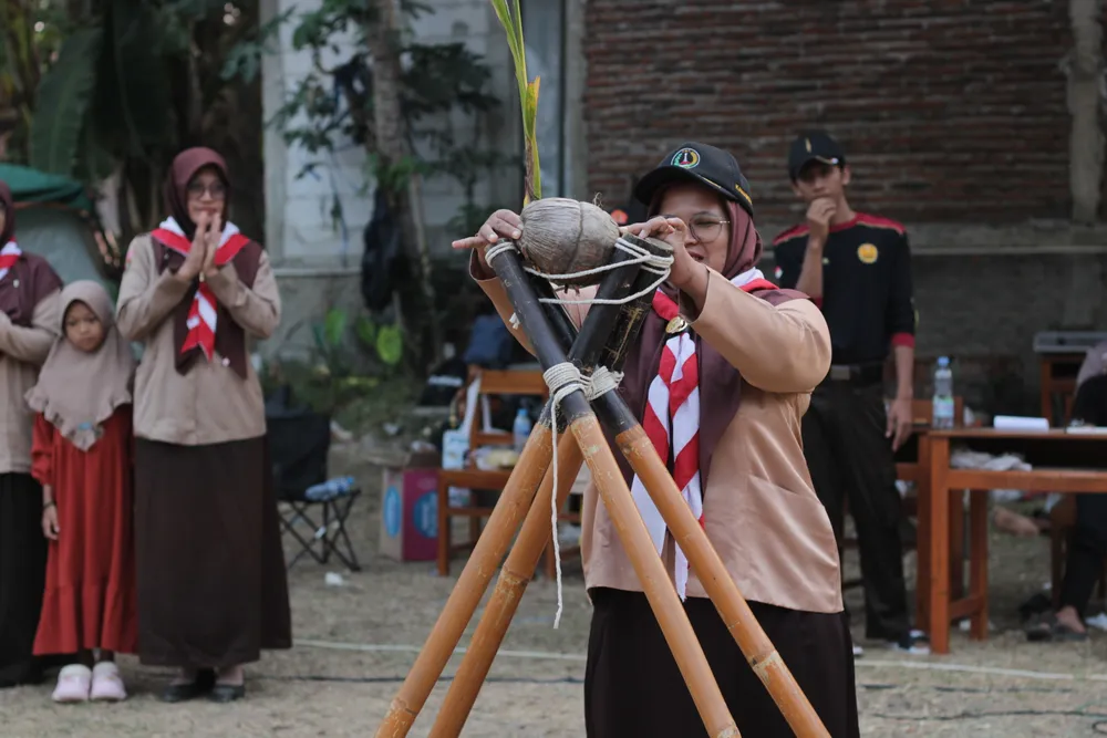 Peserta pramuka mengikat tali pada pertemuan tongkat dalam kegiatan keterampilan kepramukaan