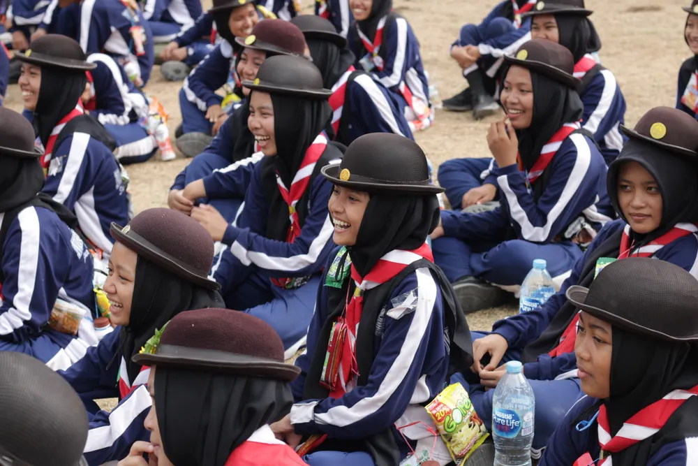 Peserta pramuka duduk bersama di lapangan dalam suasana akrab dan ceria