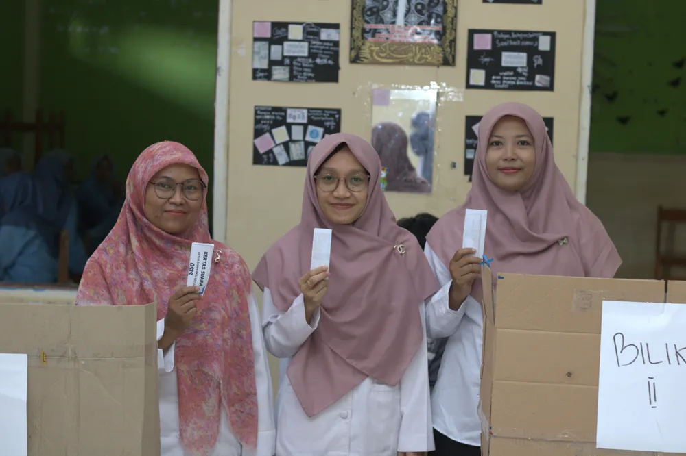 Guru menunjukkan surat suara dalam pemilihan OSIS